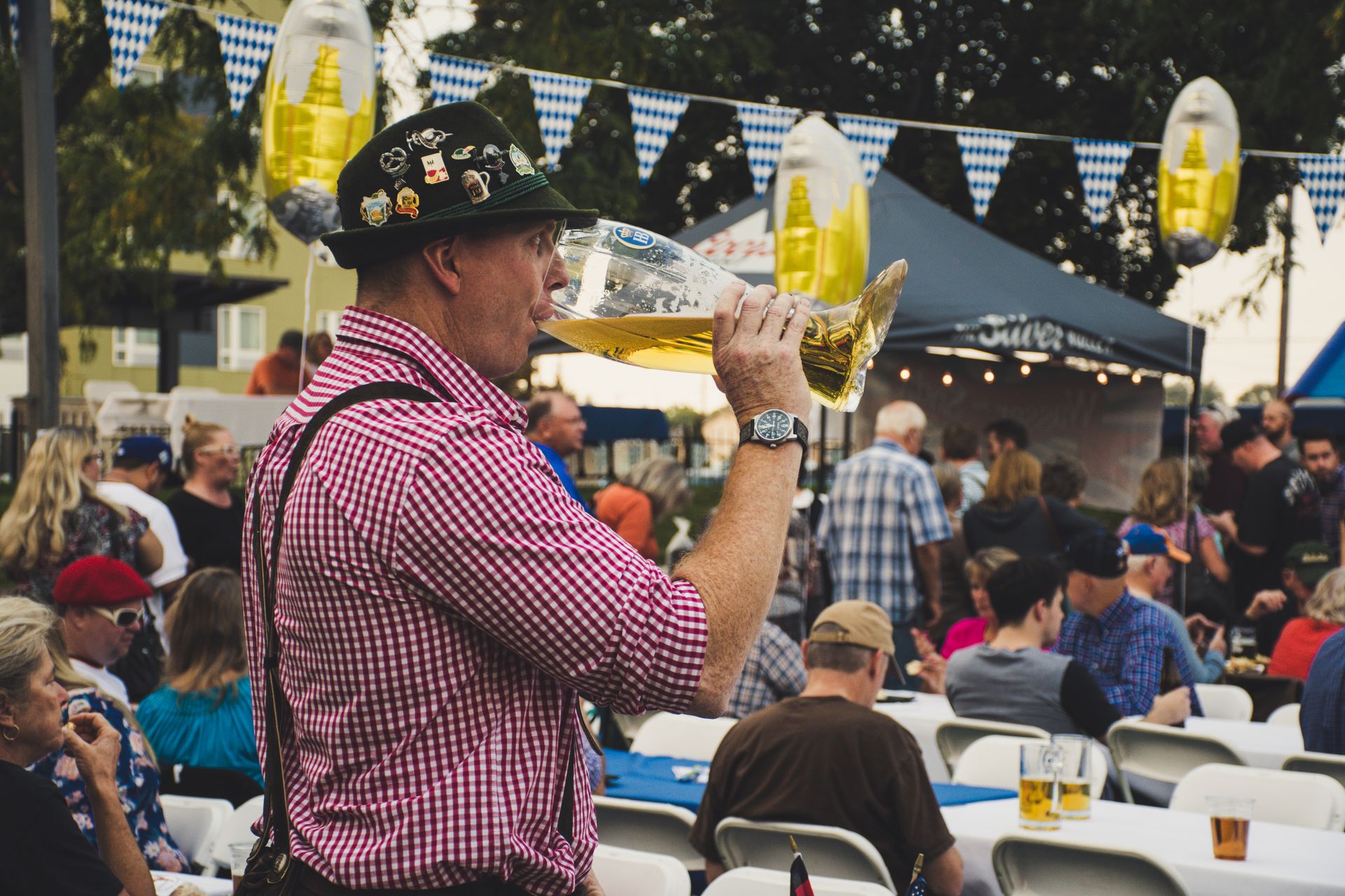 Uomo con abito bavarese che beve una Maß di birra all’Oktoberfest