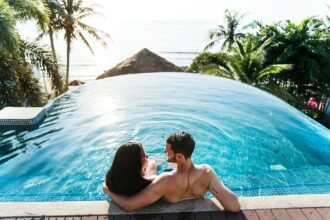 Coppia in piscina a sfioro con vista mare, atmosfera da viaggio di nozze - Foto U+