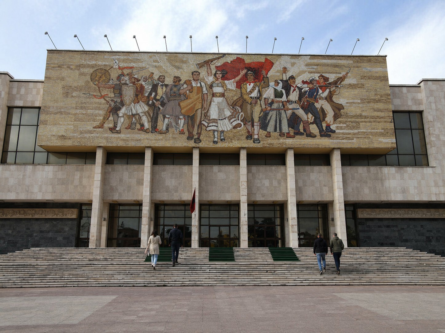Museo di Storia Nazionale a Tirana con mosaico monumentale e persone che salgono la scalinata