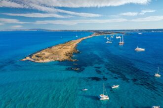 Veduta aerea delle acque turchesi tra Ibiza e Formentera con barche e velieri